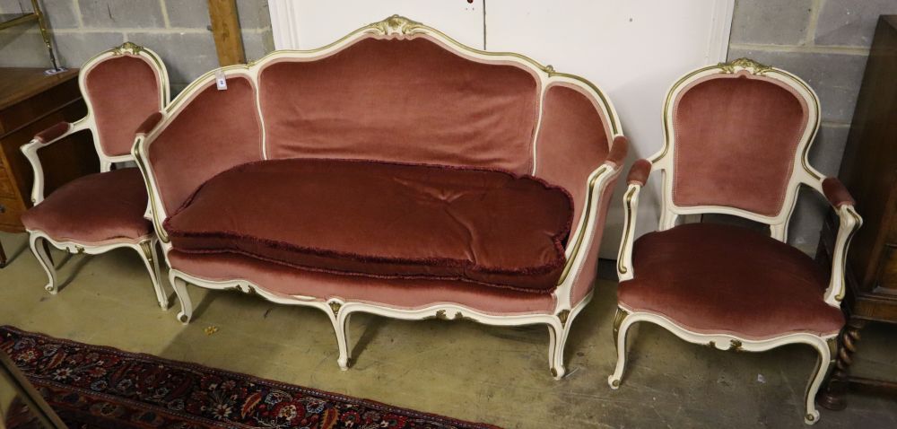 A Louis XV style cream and gilt painted carved wood framed canape and a pair of open armchairs, upholstered in pink dralon, settee widt